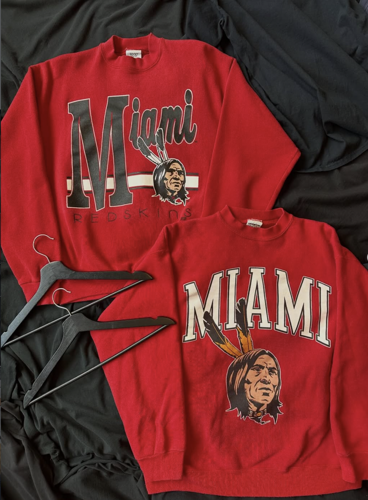 Two vintage red Miami University crewnecks hanging on black hangers.